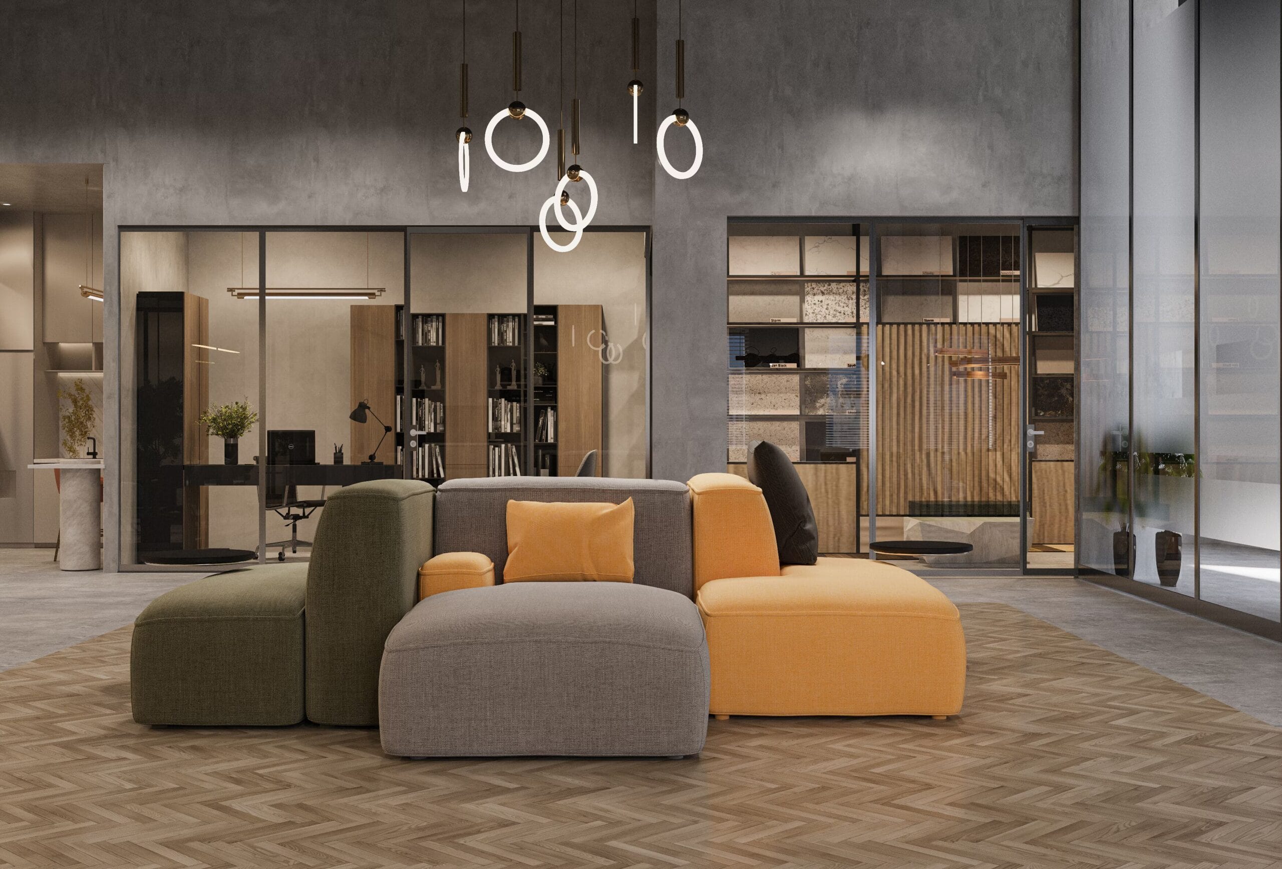 Un coin lounge cosy avec un canapé modulaire aux couleurs vives — gris, vert, jaune et noir — sous un éclairage suspendu circulaire. En arrière-plan, des bureaux vitrés et des étagères en bois.
